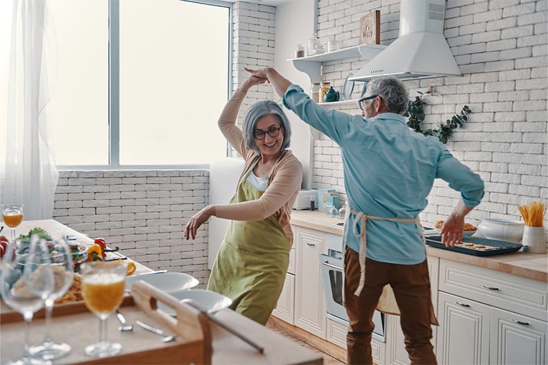 Happy older couple dancing in their kitchen are happy with their home features