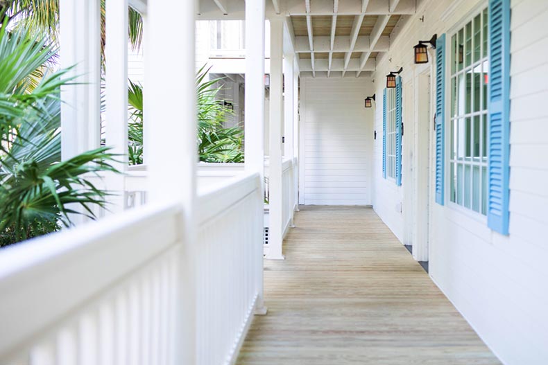 A verandah outside of an airy, white home in a warm climate