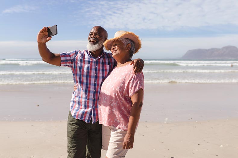 A happy snowbird couple smiling for a photo on the beach