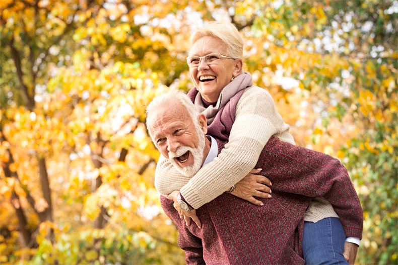 A happy older couple laughing and having fun in an autumn park