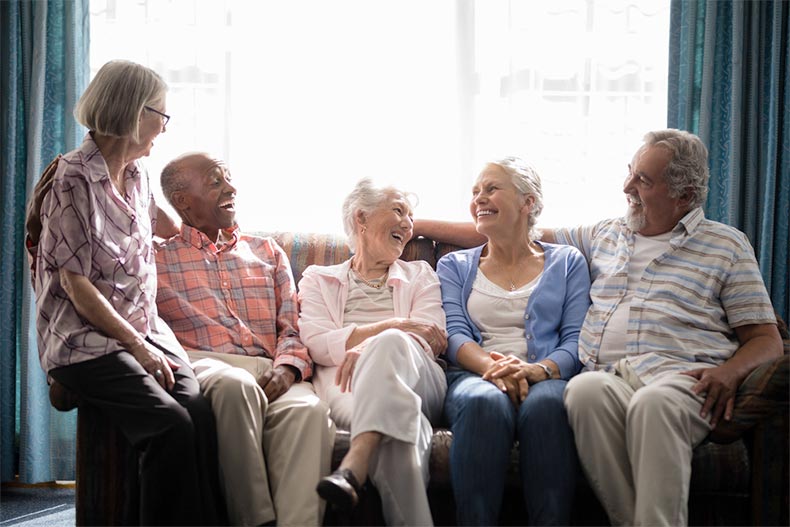 A group of senior friends sitting on a couch together and laughing