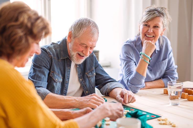 A group of older adults smiling while playing a game in a community common area