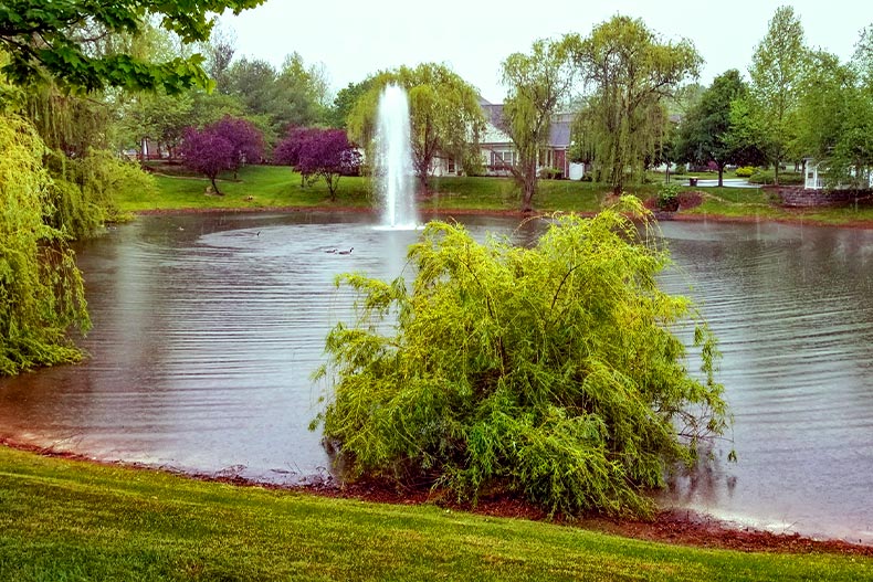 A fountain in the center of a pond surrounded by trees in Somerset Run in Somerset, New Jersey