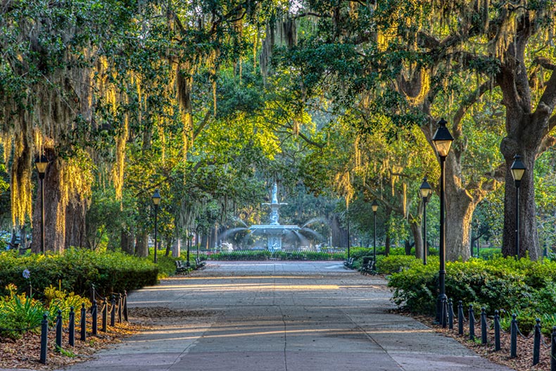 A fountain at the end of a path lined with tress covered in Spanish Moss in Downtown Savannah, Georgia