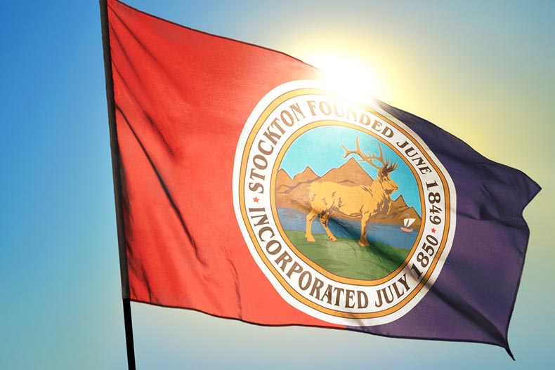 The flag for Stockton, California waving on the wind in front of the sun