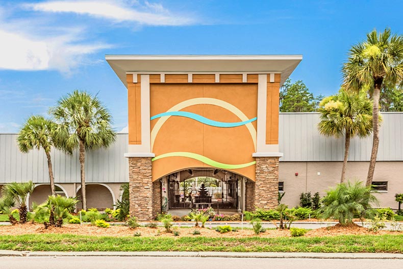 Exterior view of the clubhouse at Summertree against a blue sky and palm trees, located in New Port Richey, Florida