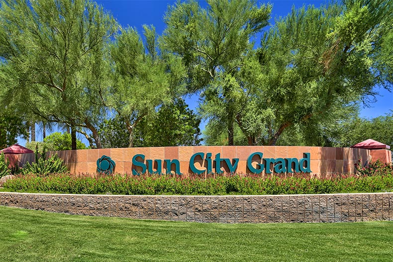 Trees and grass surrounding the community sign for Sun City Grand in Surprise, Arizona