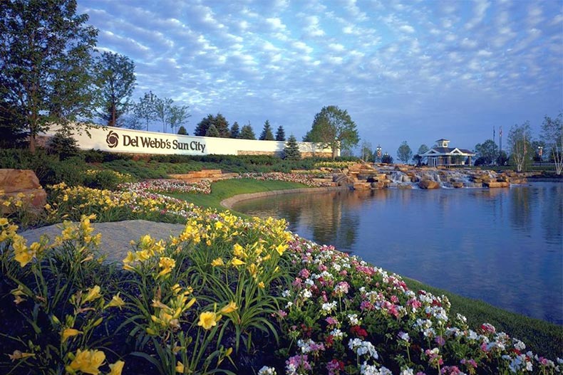 Flowers and a pond beside the community sign for Sun City Huntley in Illinois