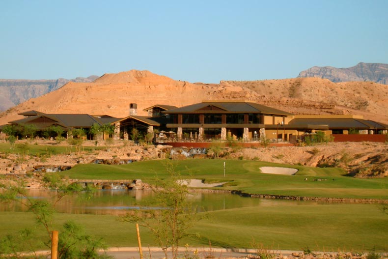Exterior view of the clubhouse in Sun City Mesquite taken from a distance with a golf course in the foreground and a mountain range in the back, located in Mesquite, Texas