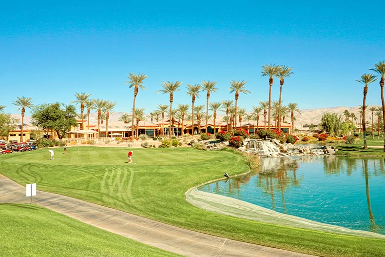 Distant view of golfers on a course near a pond in Sun City Palm Desert, California