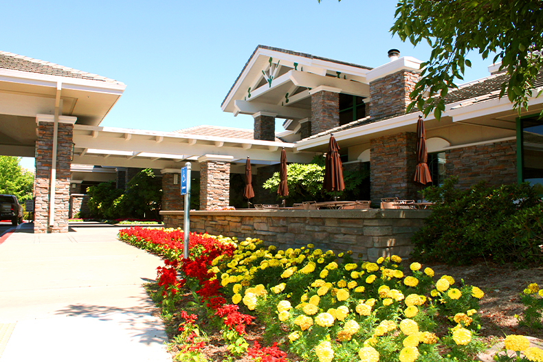 Exterior view of the clubhouse in Sun City Roseville, California with red and yellow flowers out front