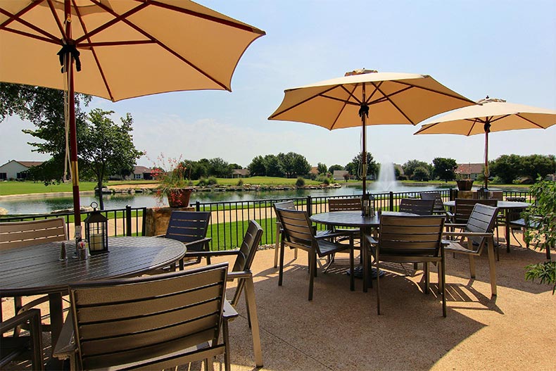 Tables and chairs on a patio overlooking a picturesque pond at Sun City Texas in Georgetown, Texas