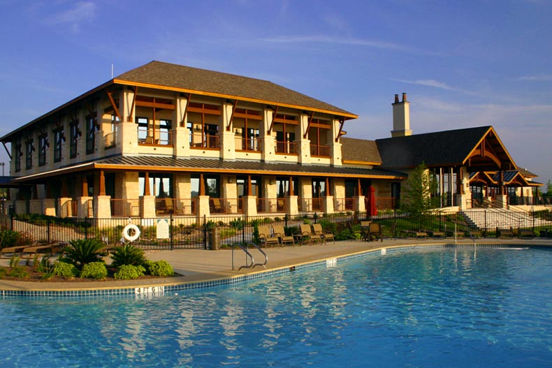 Exterior view of a clubhouse in Sun City Texas with a resort-style pool in the foreground, located in Georgetown, Texas