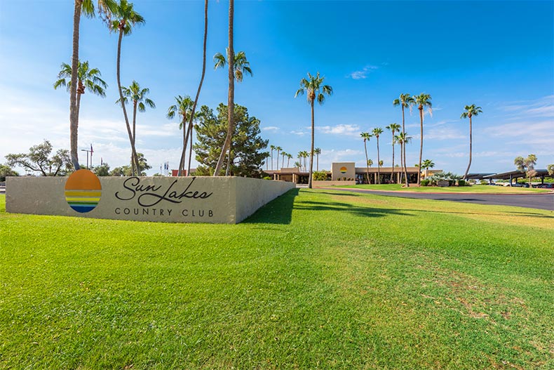 Palm trees and green grass surrounding the community sign for Sun Lakes Country Club in Banning, California