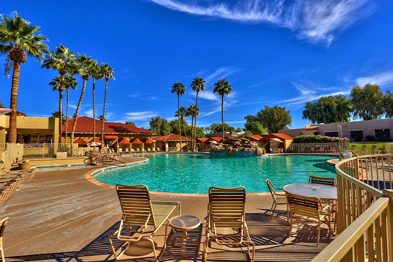 The pool and patio in Sun Village surrounded by a clubhouse and palm trees, located in Surprise, Arizona