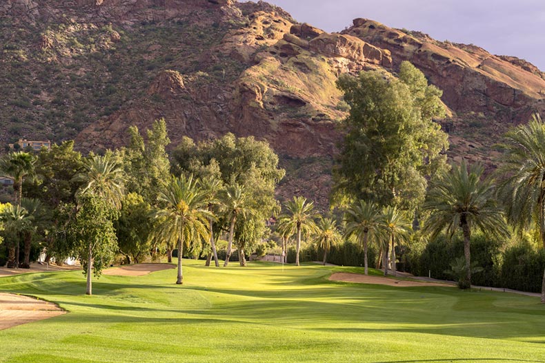 A golf course fairway bathed in sunlight with Camelback Mountain in background in Phoenix, Arizona