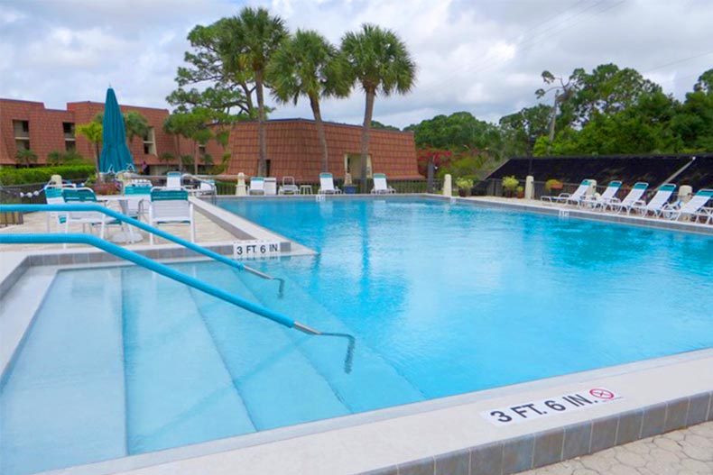 Lounge chairs and palm trees surrounding the outdoor pool at Tarpon Bay Yacht Club in Port St. Lucie, Florida