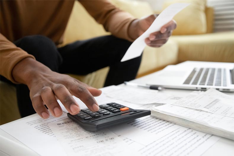 Close up of an older man's hands using a calculator to manage household finances and file taxes