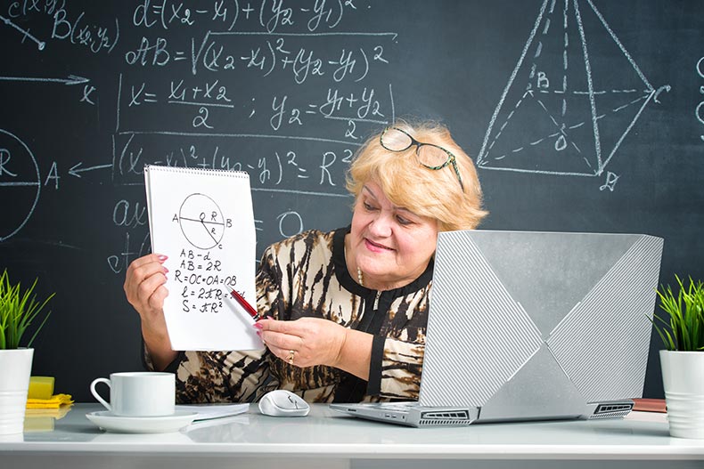 A teacher conducting an online lesson for students on a laptop at home