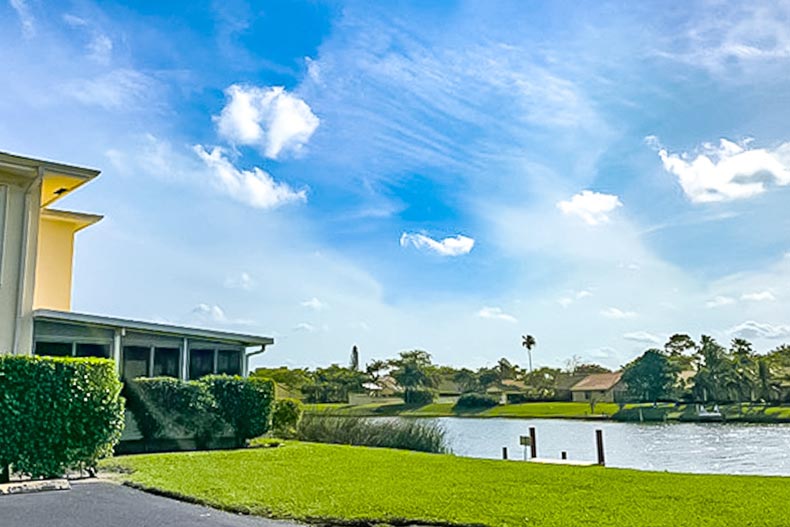 Homes and greenery surrounding a picturesque pond in The Pines Of Delray in Delray Beach, Florida
