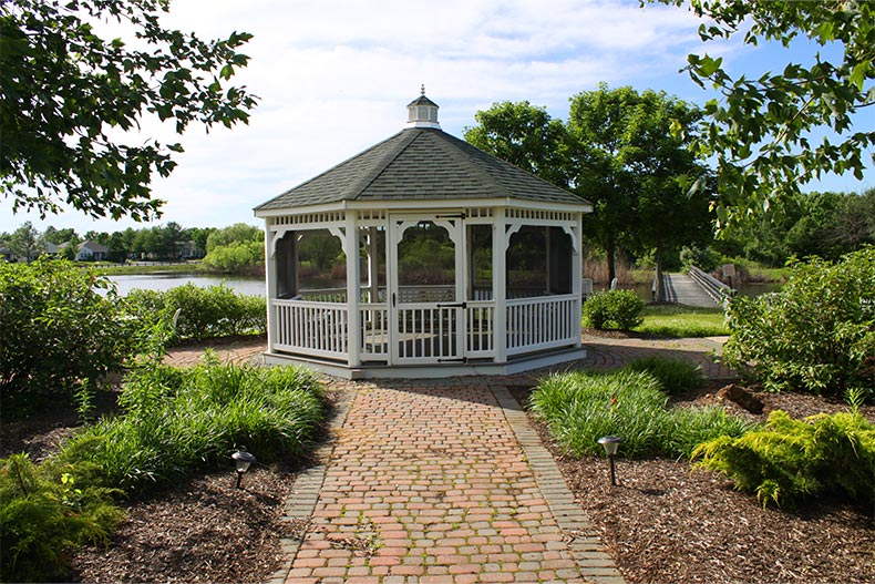 A brick path leading to a gazebo surrounded by greenery at The Ponds in Monroe, New Jersey