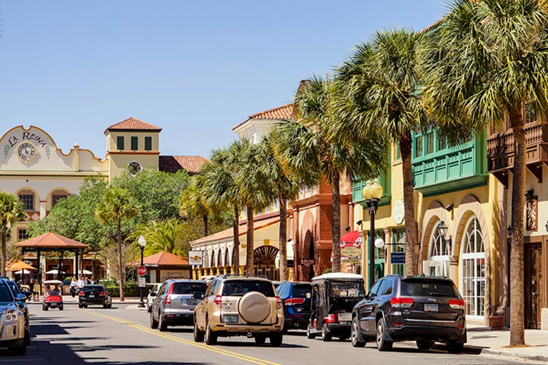 Cars and palm trees along a street lined with shops at The Villages in Florida