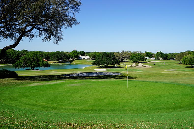 Een blauwe lucht boven een golfbaan met een vijver bij The Villages in Florida