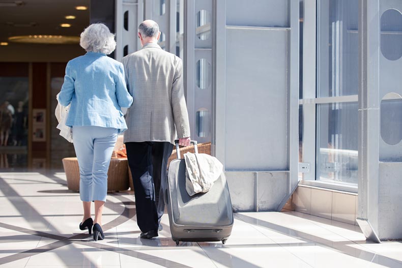 A snowbird couple with their luggage getting ready to board a plane