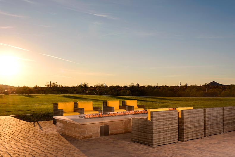 View of chairs on a patio by an outdoor fireplace in Trilogy at Vistancia, Peoria, Arizona