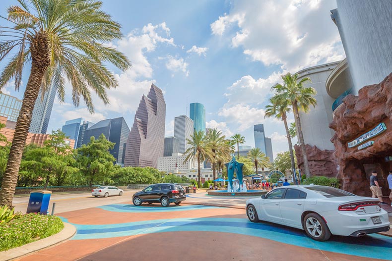Cars driving up to the entrance of the Downtown Aquarium near a fountain with swordfish in Houston, Texas