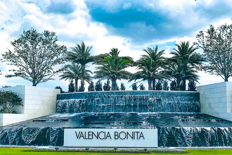 Palm trees and a water feature beside the community sign for Valencia Bonita in Bonita Springs, Florida