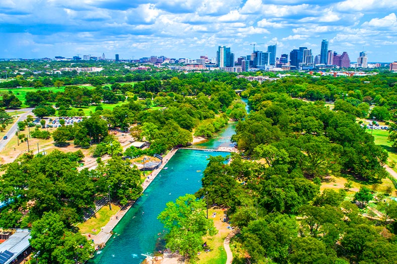 Drone shot of Barton Springs in Austin, Texas with the city skyline in the background