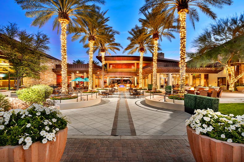 View of a courtyard outside of a clubhouse with palm trees decorated with Christmas lights, located in Trilogy at Vistancia of Peoria, Arizona