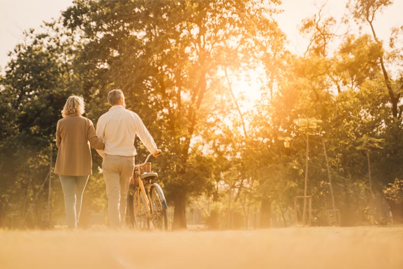 A senior couple walking their bike along a trail in their 55+ community