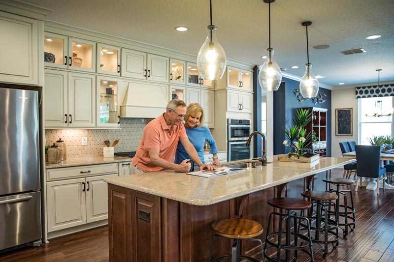 Couple stands over a kitchen island in a spacious kitchen at WaterSong at RiverTown