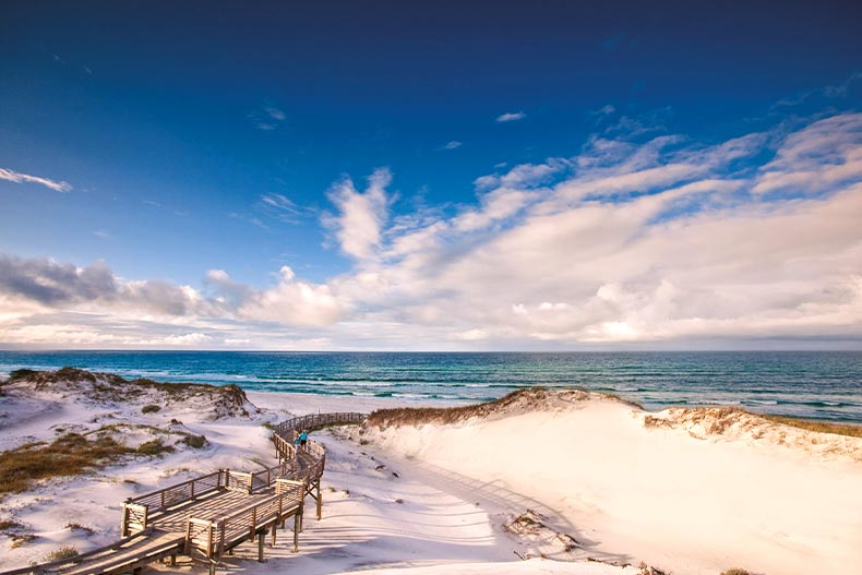 Overhead view of a wooden pathway and white sand beach in Watersound, Florida