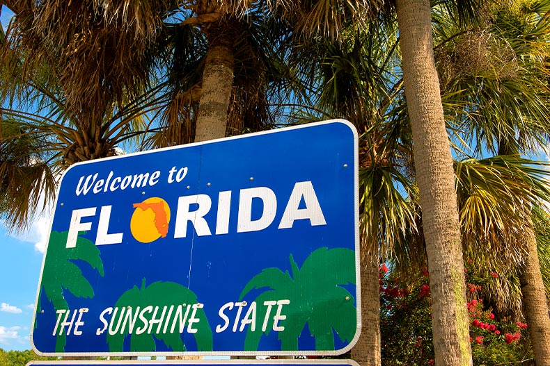 A blue welcome to Florida, The Sunshine State sign with palm trees behind