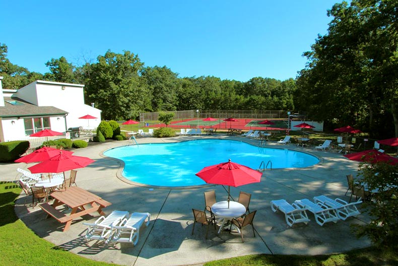  Overhead shot of an outdoor pool and patio with tables covered by large red umbrellas, located in Oaks at Weymouth, Mays Landing, New Jersey