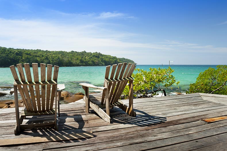 Two empty chairs on a deck overlooking the ocean