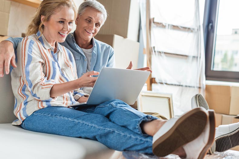 A 55+ couple sitting and using laptop to find a new house