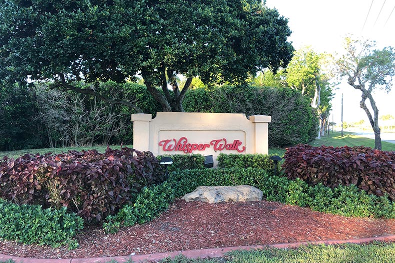 Greenery surrounding the community sign for Whisper Walk in Boca Raton, Florida