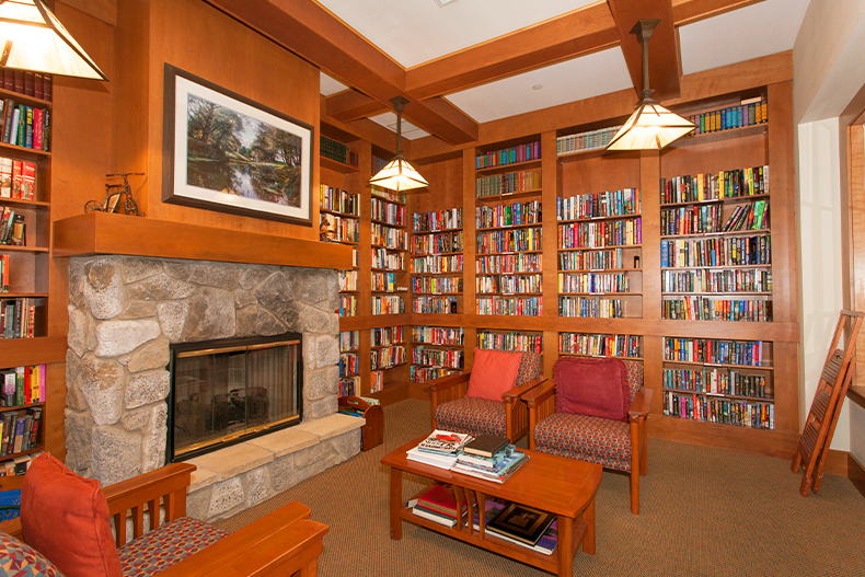 Interior view of a library lounge in Springfield at Whitney Oaks with seating, a table, and a fireplace, located in Rocklin, California