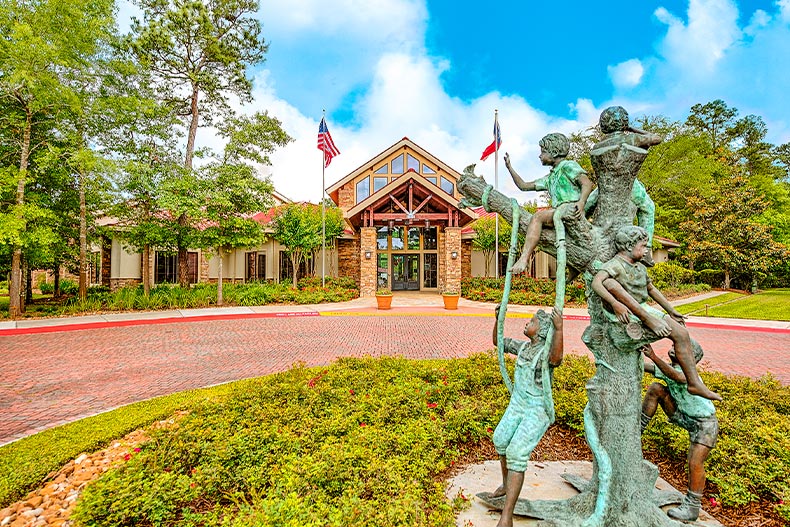 An oxidized statue of children playing on a tree located outside of the clubhouse in Windsor Lakes of The Woodlands, Texas