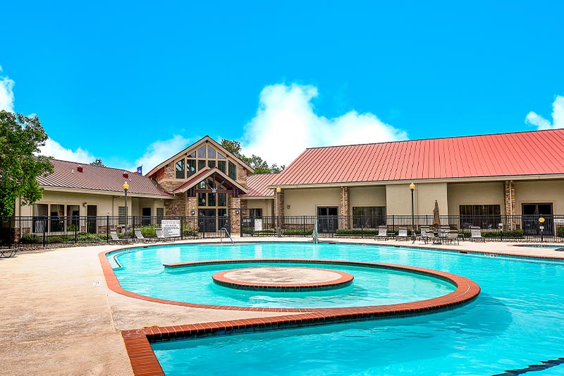 View of the outdoor pool at Windsor Lakes with the clubhouse in the background.