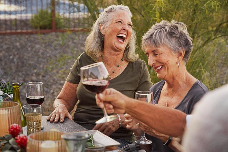 Friends laughing while enjoying an outdoor dinner at a 55+ community