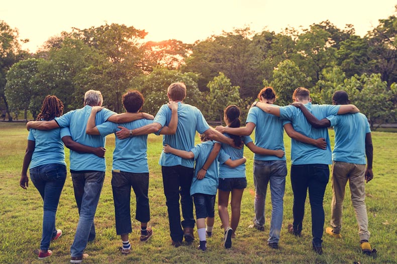 A diverse group of volunteers with their arms around each other