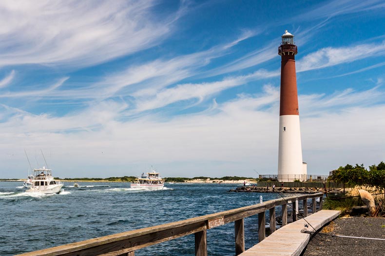 Fishing boats heading out to sea with the Barnegat Lighthouse in the background