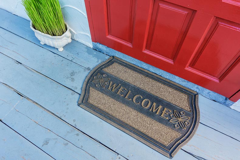The "welcome" mat outside a red front door